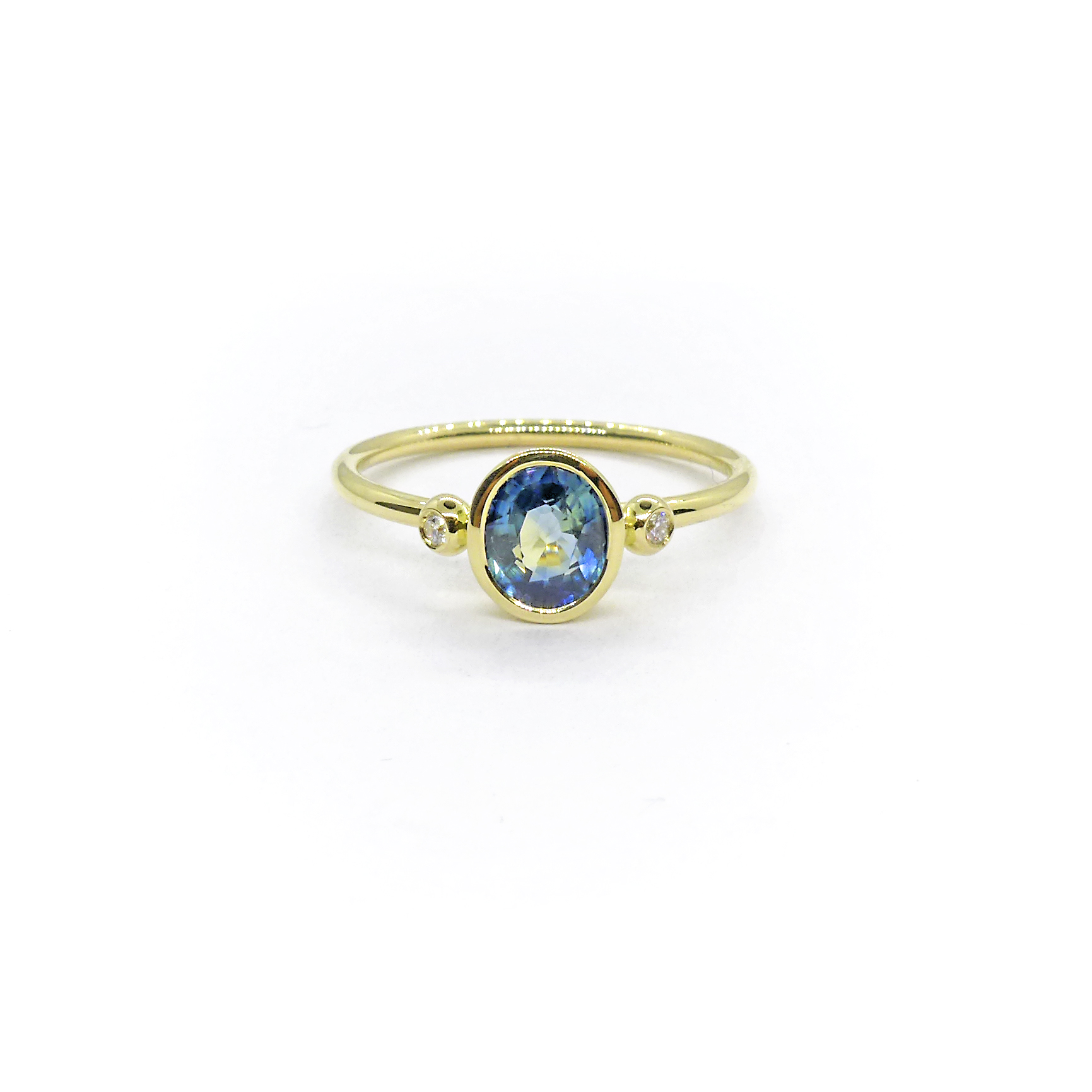 yellow gold ring with an oval blue sapphire and two small diamonds next to it